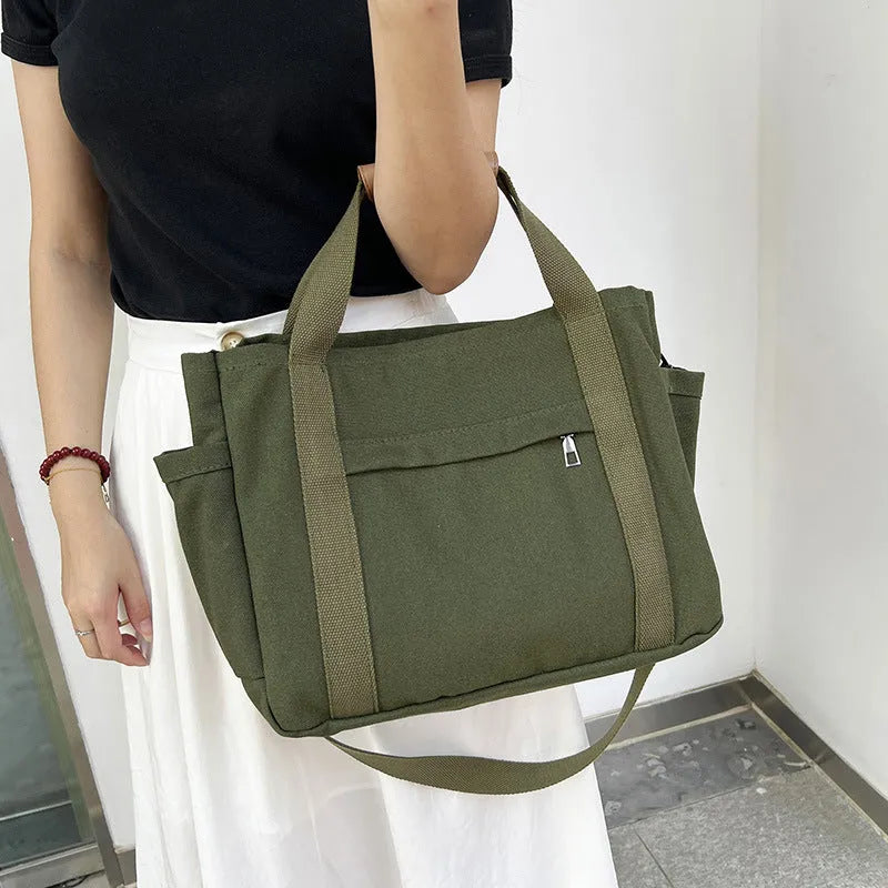 Canvas crossbody tote bag in khaki with open zipper showing internal organiser pockets.