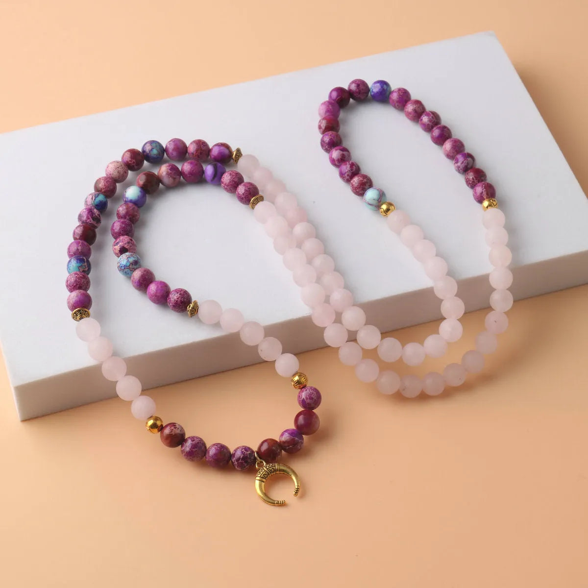 Close-up of a pink emperor stone crystal bead pendant on a necklace chain for casual wear.