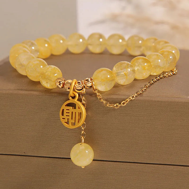 Women's natural citrine bracelet with gold electroplated Chinese character charm on an adjustable dark cord.