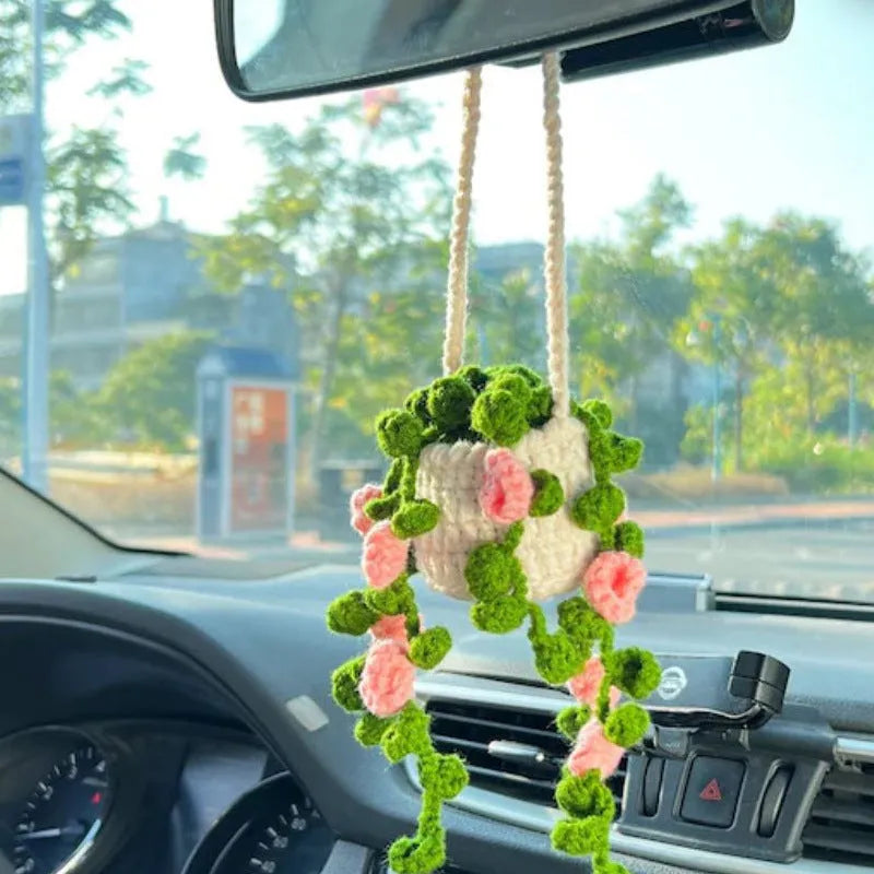 Green and white knitted wool car plant ornament with basin base and hanging rope.