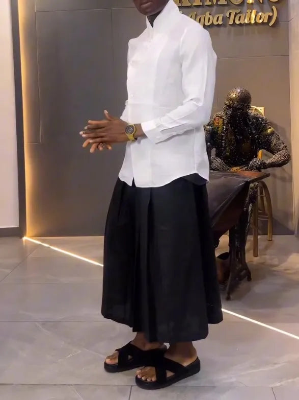 White asymmetric long sleeve shirt and black pleated trousers co-ord set on a hanger
