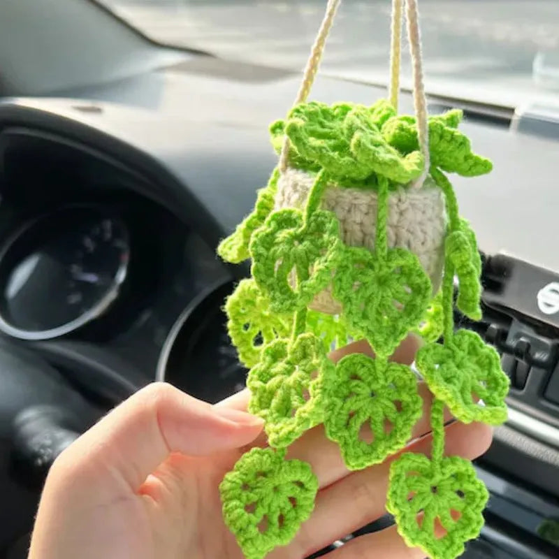 Green and white knitted wool car plant ornament with basin base and hanging rope.