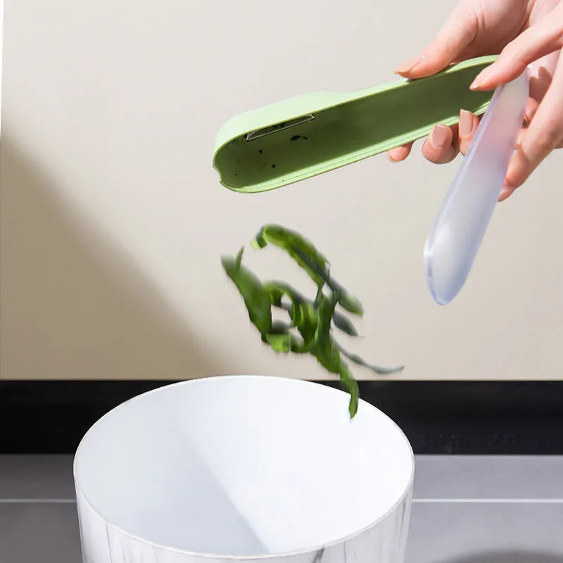 Green kitchen peeler with stainless steel blade stored inside a clear plastic tube.