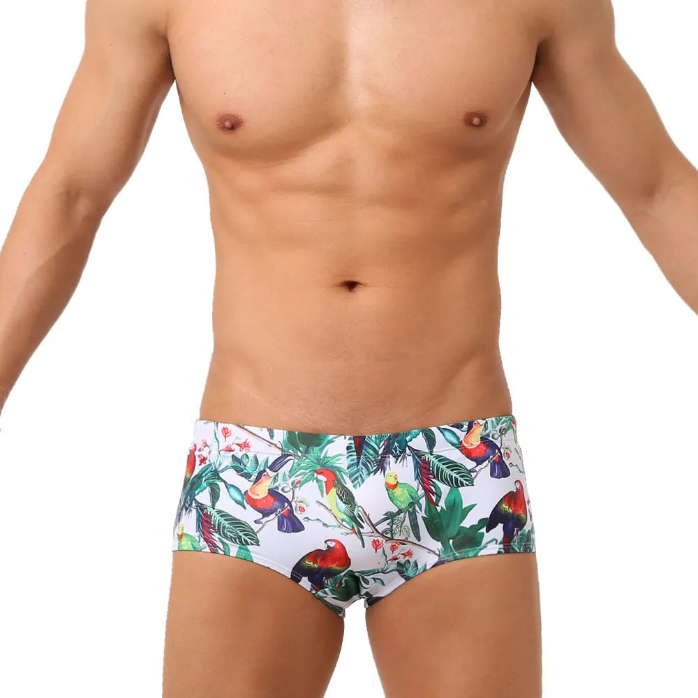 Men's blue swimming trunks with a colourful flowers and birds print, showing the boxer style and cup cover.