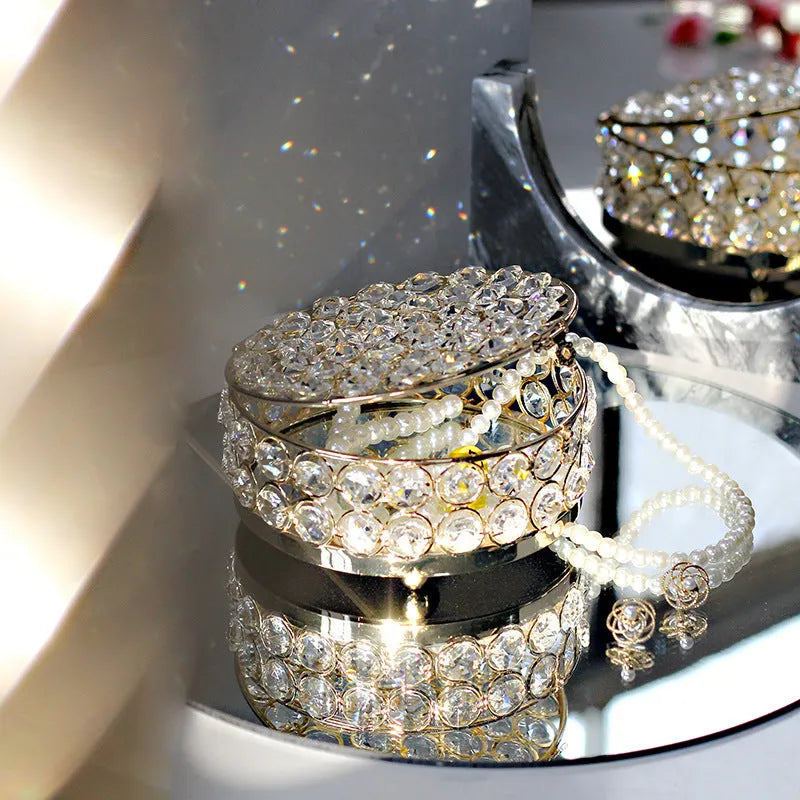 Transparent crystal glass jewelry storage box with ornate French gold metal frame.