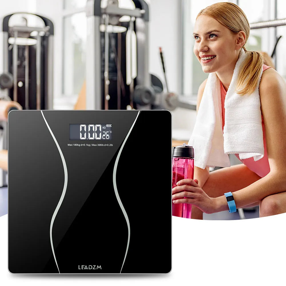 Black electronic bathroom scale with digital display on tempered glass platform
