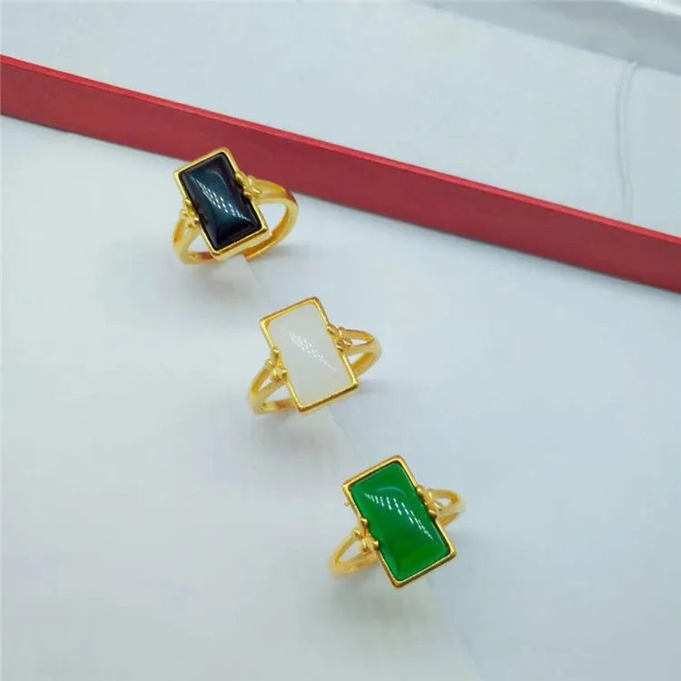 Adjustable gold-plated brass ring with a black electroplated gemstone on a neutral background.