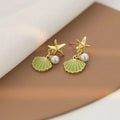14K gold starfish shell earrings in light green on a white background