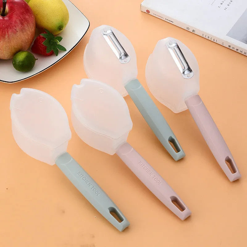Stainless steel handle fruit peeler in pink colour with PP plastic body on a wooden surface
