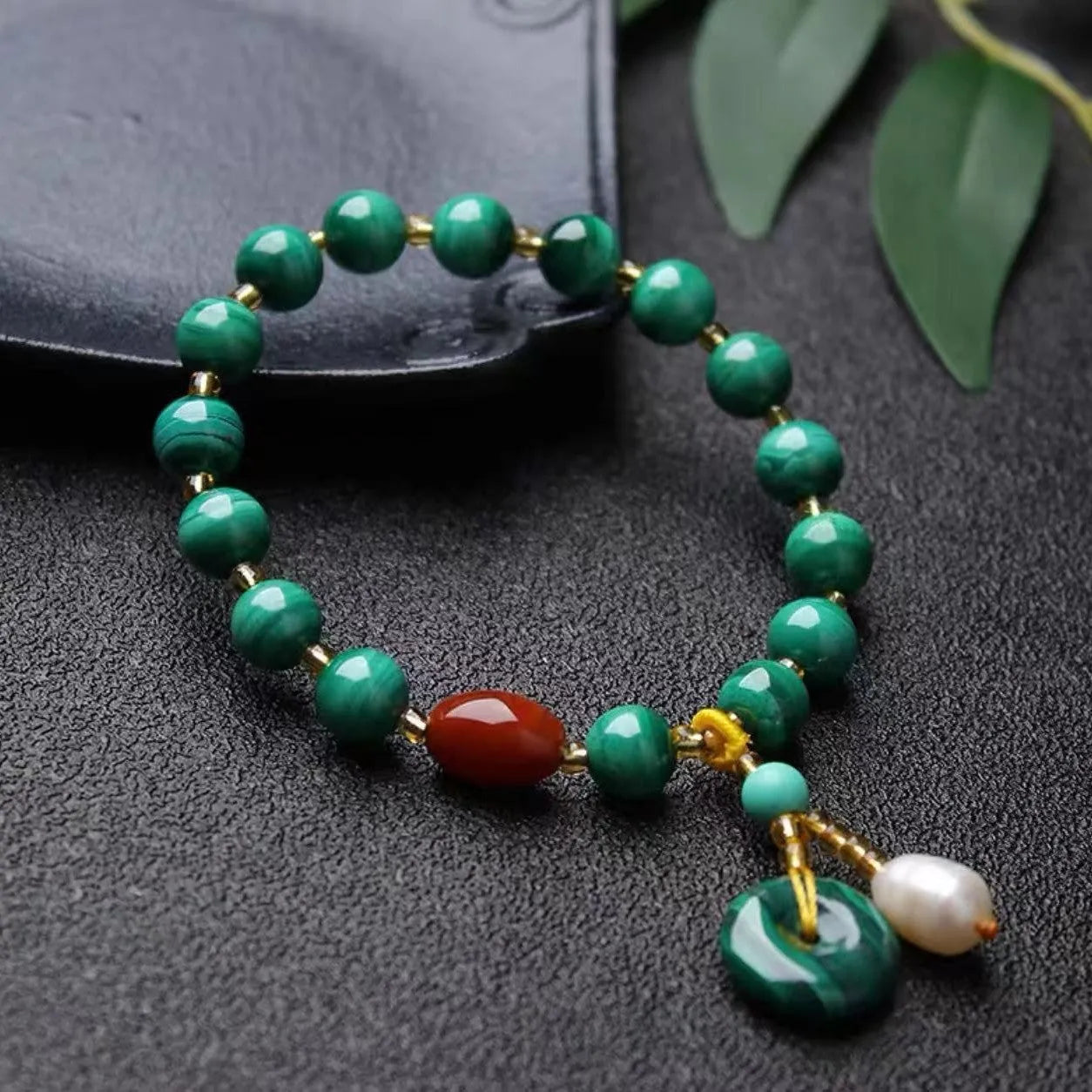 Natural green malachite bracelet with barrel-shaped beads on a wrist.