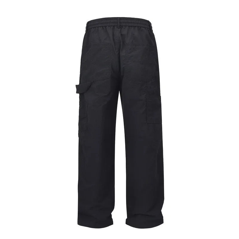 Black men's baggy paratrooper pants with an elastic drawstring waist on a neutral background.