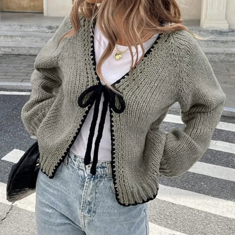 Gray lace-up cardigan sweater with crocheted flower detail and long sleeves on a hanger