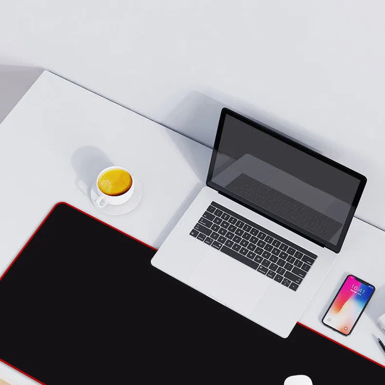 Extra long black mouse pad with stitched edges on a desk showing keyboard and mouse placement