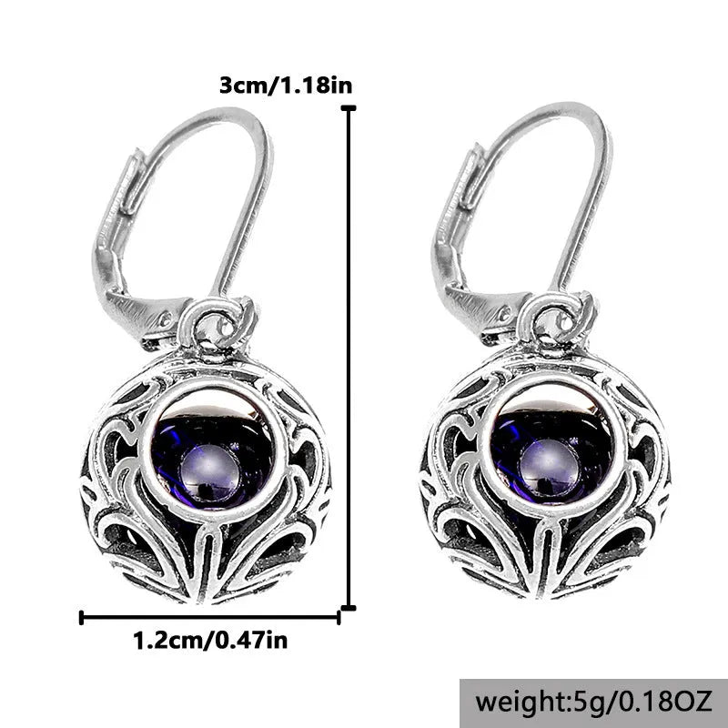 Silver geometric hollow pendant earrings with vintage engraving and a central blue gemstone on a zinc alloy setting.