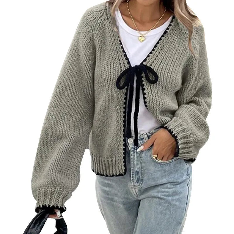 Gray lace-up cardigan sweater with crocheted flower detail and long sleeves on a hanger