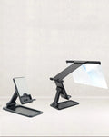 Black folding mobile phone screen magnifier with detachable holder next to an iPhone