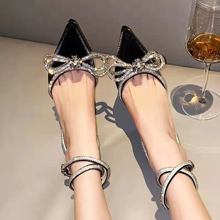 Women's black stiletto sandals with silk-like bandage across heel and gold buckle closure.