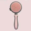 Pink and green double-sided cat brush with flea comb and release button for pet grooming.