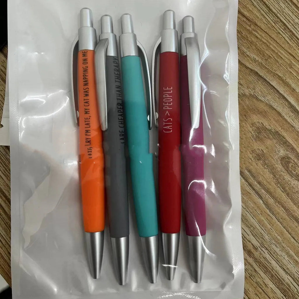 Set of five coloured push action automatic pens in a cat-themed or dog-themed design, next to a beaded storage bag.