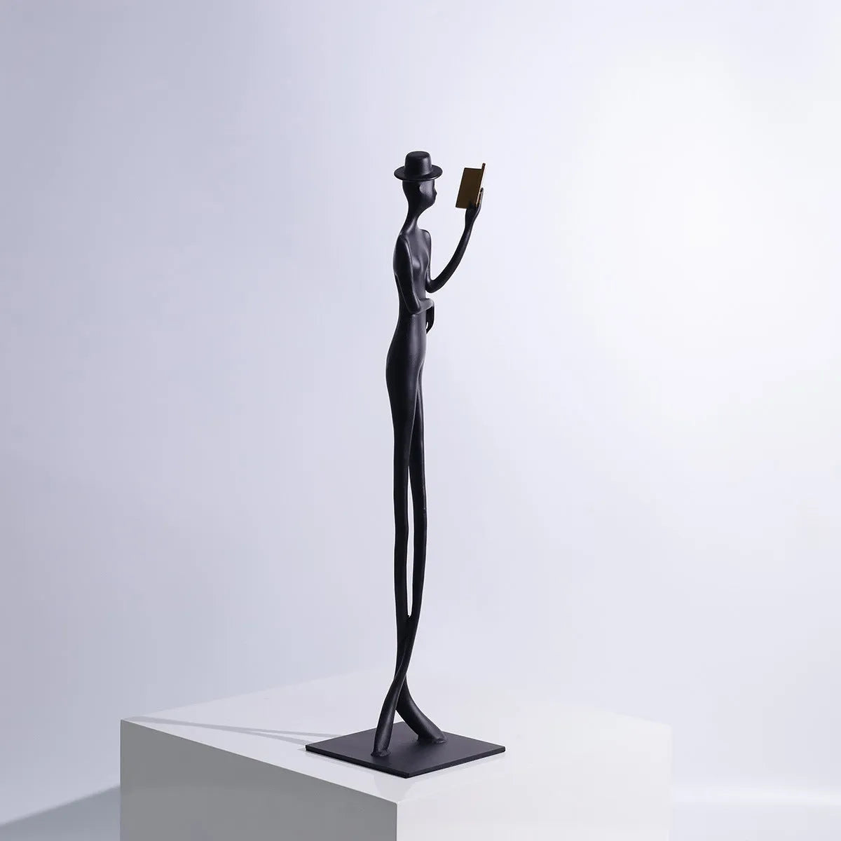 Black metal cast aluminium reading woman sculpture on desk, modern minimalist style