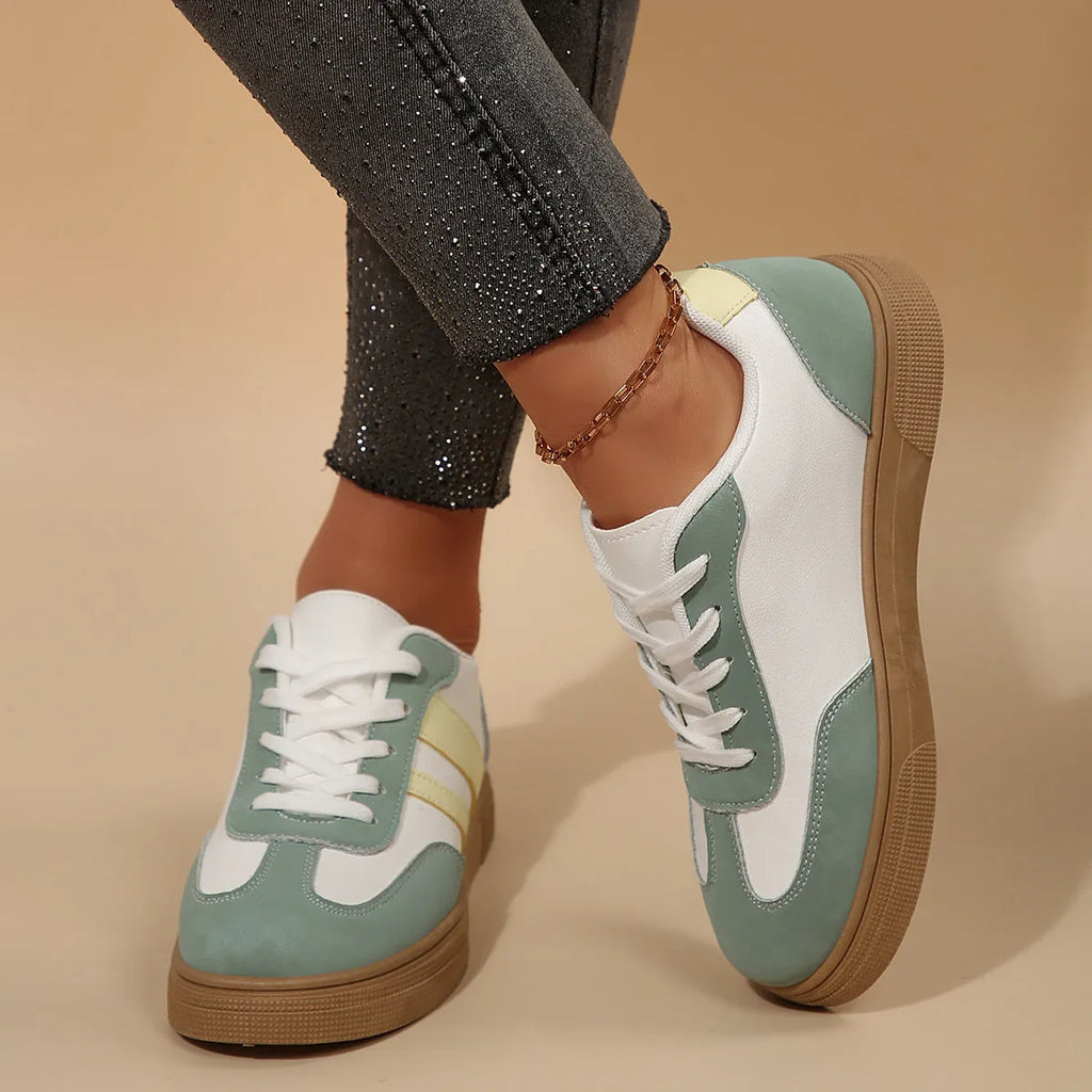 Green women's retro sneakers with cross-strap detail and leather stitching on a white background.