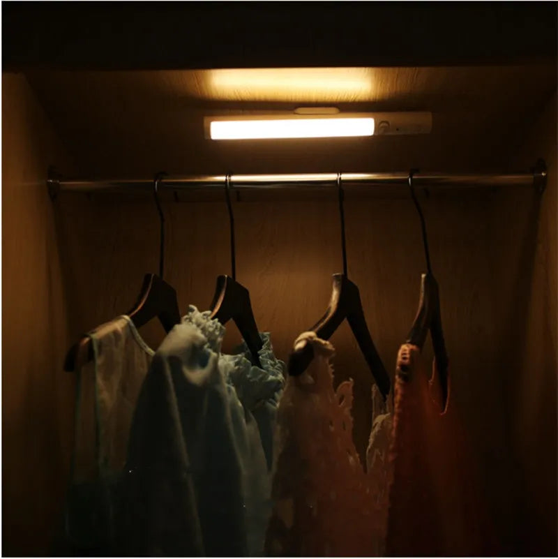 Slender white human body induction cabinet light with magnetic strip for mounting on metallic surfaces.