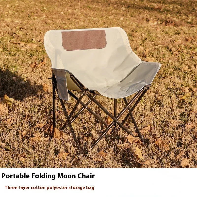 Beige portable folding camping chair with steel frame on grass outdoors