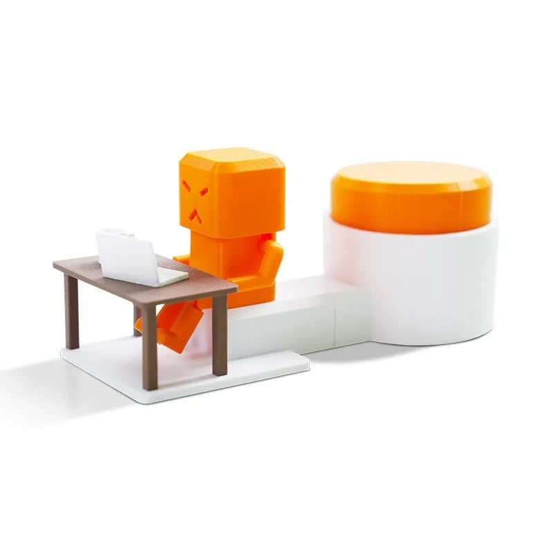 Orange plastic decompression toy with a table-turning mechanism on a desk.