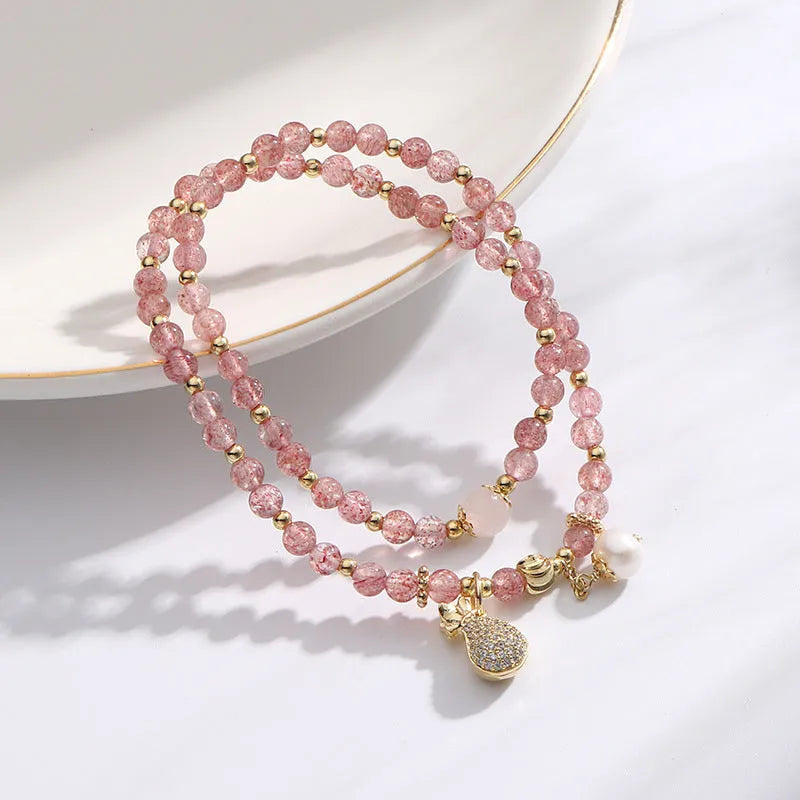 Women's geometric strawberry quartz crystal wallet bracelet on a wrist.