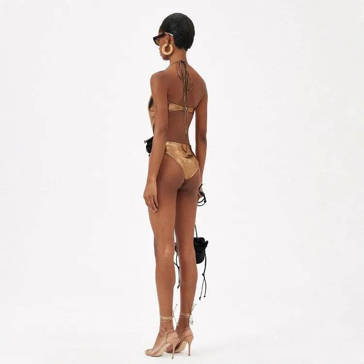 Gold coloured handmade one-piece swimsuit with halter neckline and hollow-out design on a mannequin.