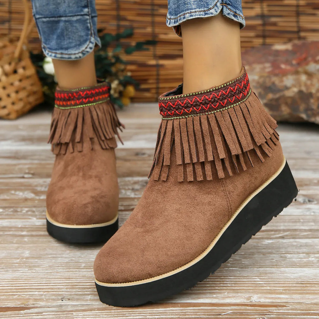 Women's suede ankle boot with wedge heel, side zipper, tassel detail, and thick rubber sole in three colour options.