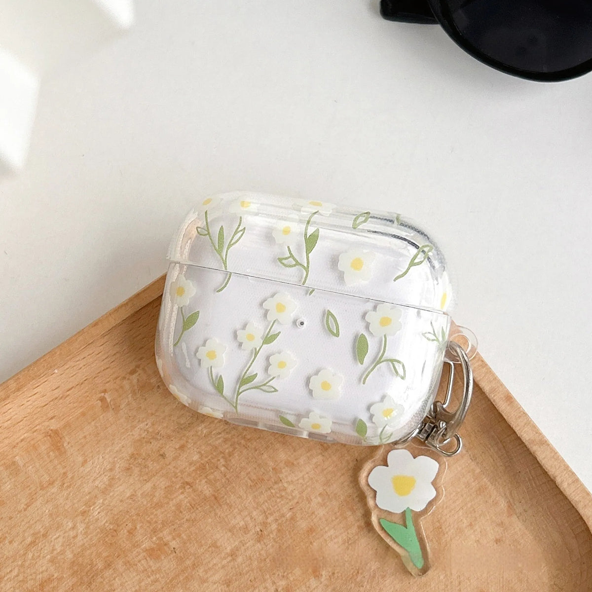 Transparent white floral patterned soft TPU protective case for Apple AirPods on a table.