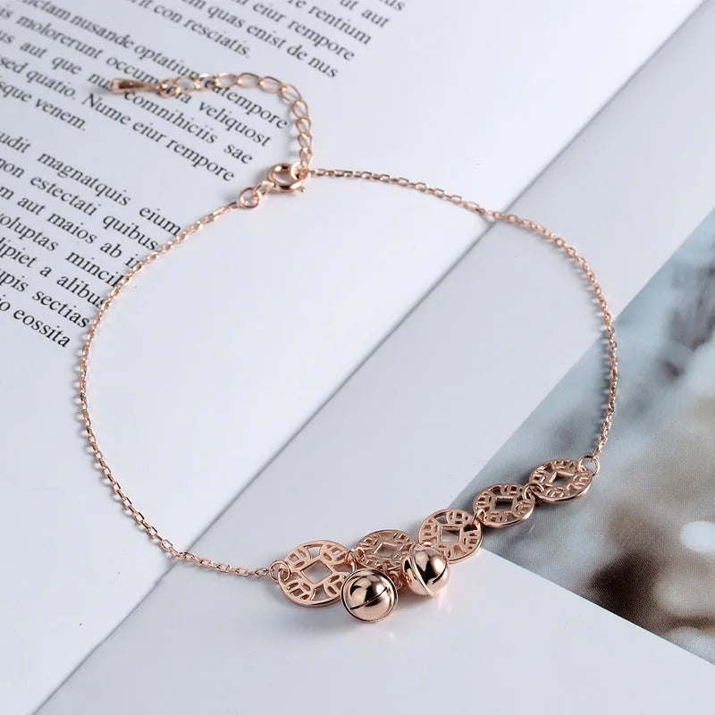 Rose gold stainless steel anklet with coin charms and small bells on adjustable link chain