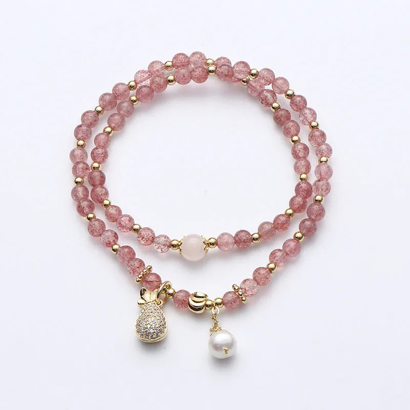 Women's geometric strawberry quartz crystal wallet bracelet on a wrist.