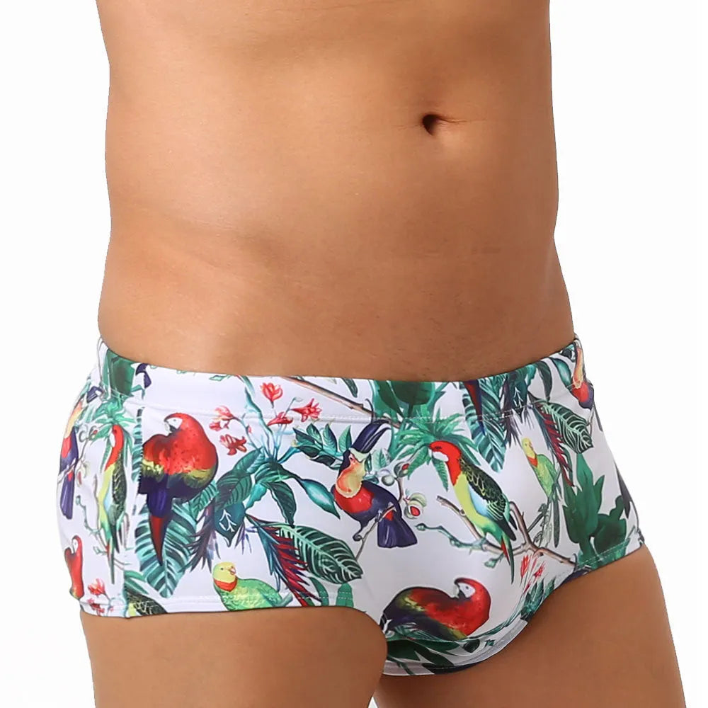 Men's blue swimming trunks with a colourful flowers and birds print, showing the boxer style and cup cover.