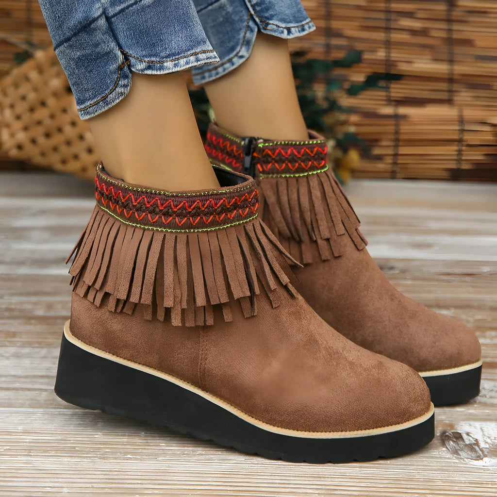 Women's suede ankle boot with wedge heel, side zipper, tassel detail, and thick rubber sole in three colour options.