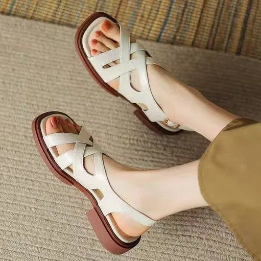Women's glossy patent leather square toe sandals with winding tape fastening on a neutral background.