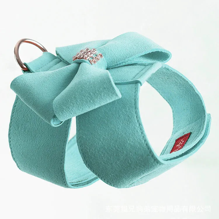 Pink microfiber dog harness with a large bowknot on the chest, shown alongside blue and orange colour options.