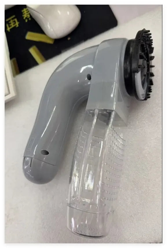 Grey portable pet hair vacuum cleaner with soft rubber grooming head on a fabric sofa