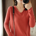 Women's long sleeve V-neck knitwear top in turmeric colour, laid flat to show pullover style and non-ironing fabric.