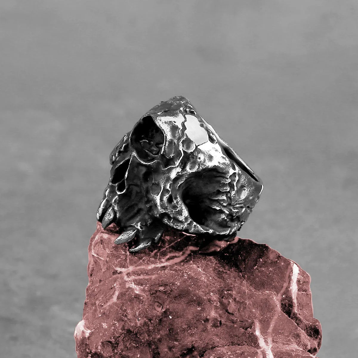 Silver tone alloy ring featuring a detailed one-eyed skull design on a black background.