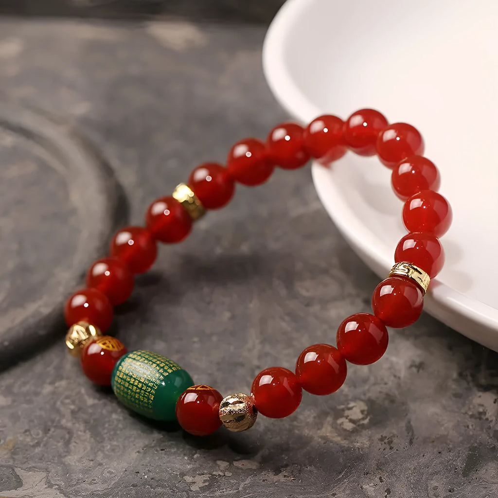 Close-up of a red agate Guanyin bracelet with detailed rosary bead edging on a wrist.