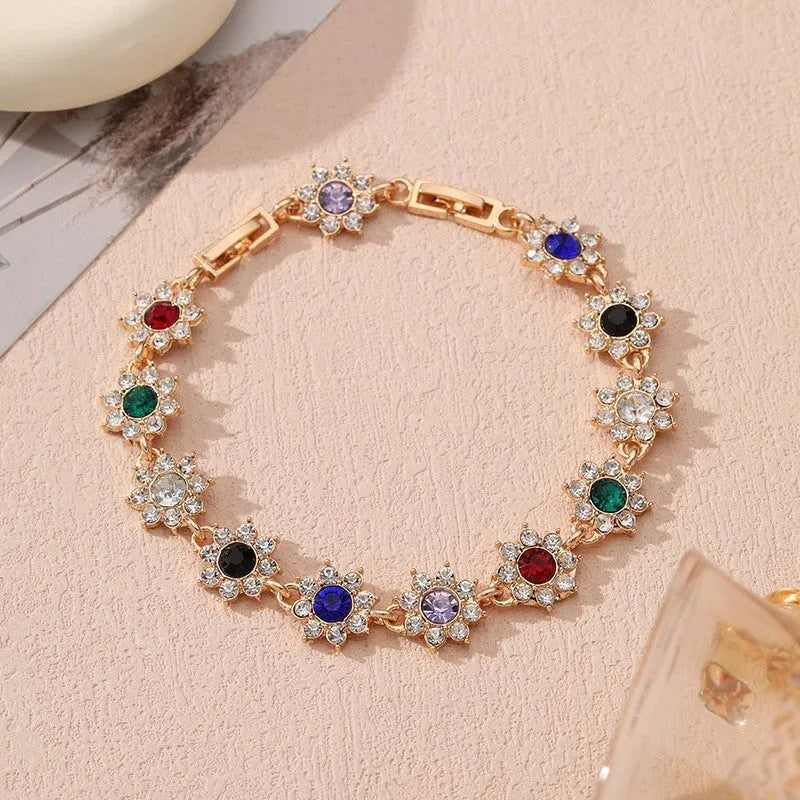 Gold and silver flower bracelet with colourful crystal and simulated diamond stones on a wrist.