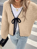 Gray lace-up cardigan sweater with crocheted flower detail and long sleeves on a hanger