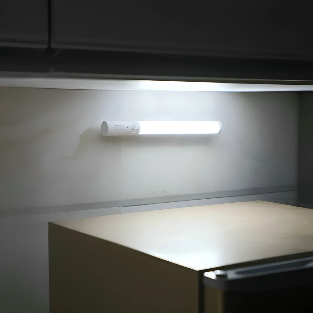 Slender white human body induction cabinet light with magnetic strip for mounting on metallic surfaces.