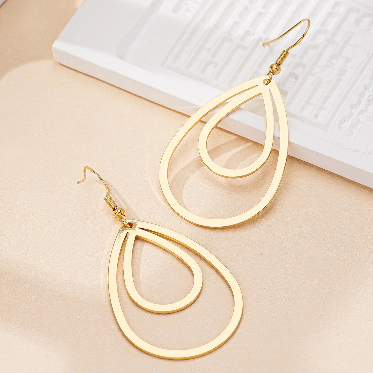 Golden yellow hollow drop earrings made from iron, shown as a pair with an open drop shape