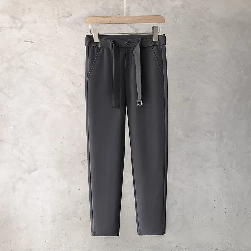 Boy wearing slim straight tapered wool trousers in a grey colour, showing the straight leg opening and belt loops.
