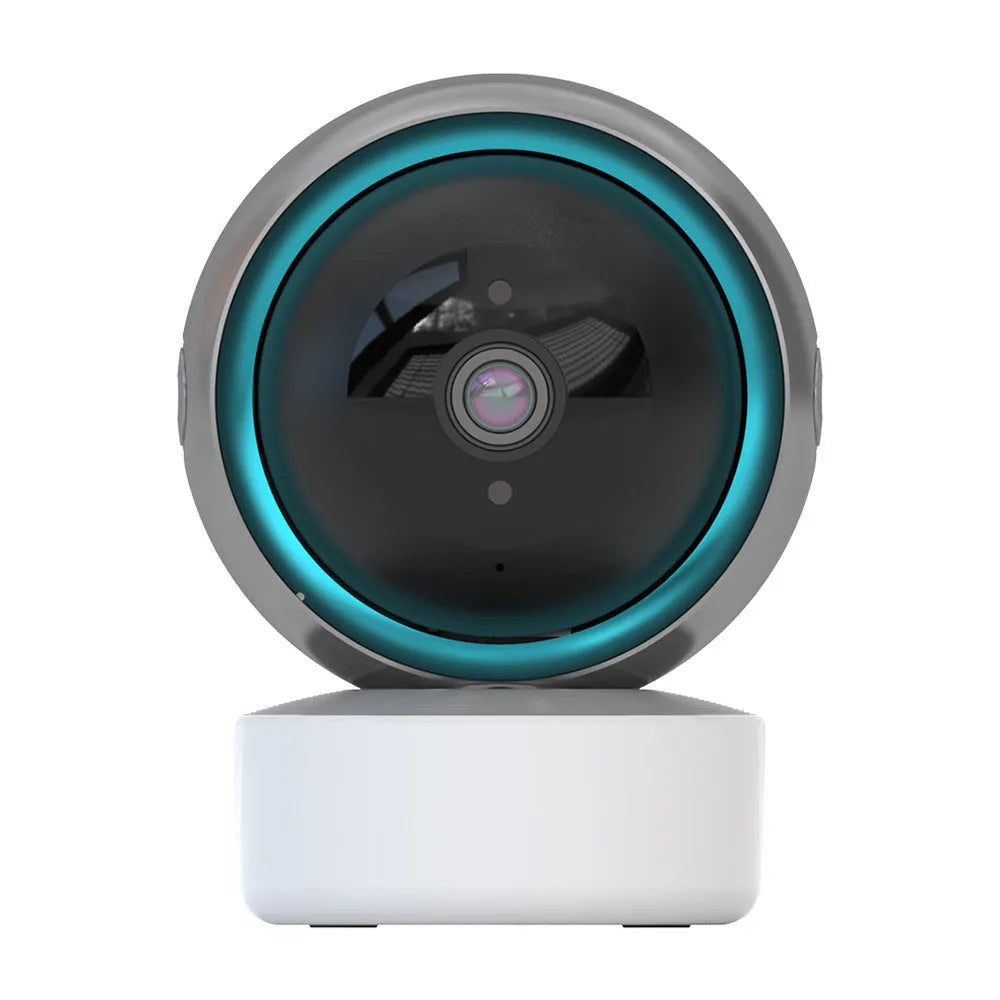 White 360-degree rotating indoor Wi-Fi security camera on a table with a UK plug power cord.