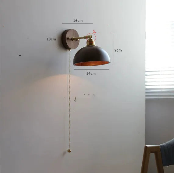 Nordic style wood finish wall lamp mounted beside a bed.