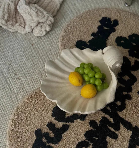White resin fruit plate ornament with detailed simulation shell design on a table.